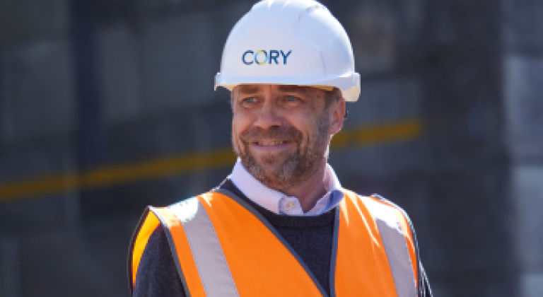 Man in a high vis vest and a 'Cory' helmet